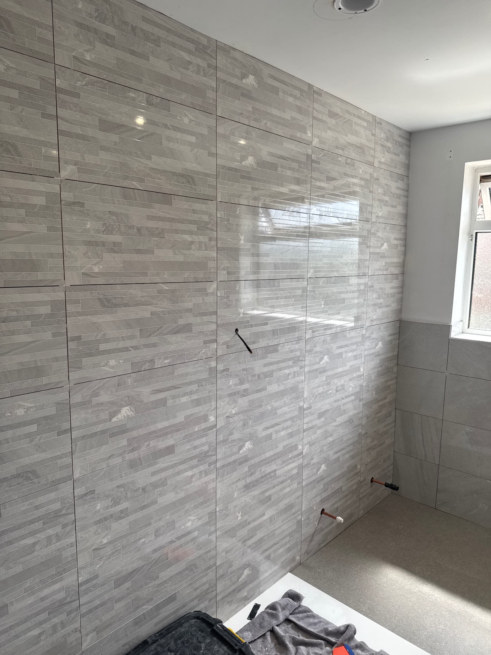 We've got the tiling complete on both the walls and floor, and we're now ready to move on to grouting and fitting the units and sanitaryware to finish off the space.