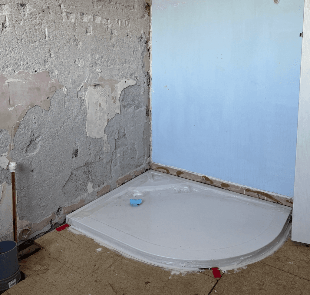 We've got the shower tray bedded in and the pipework rerouted to fit the new layout. Now we're getting the walls prepared and ready for tiling.